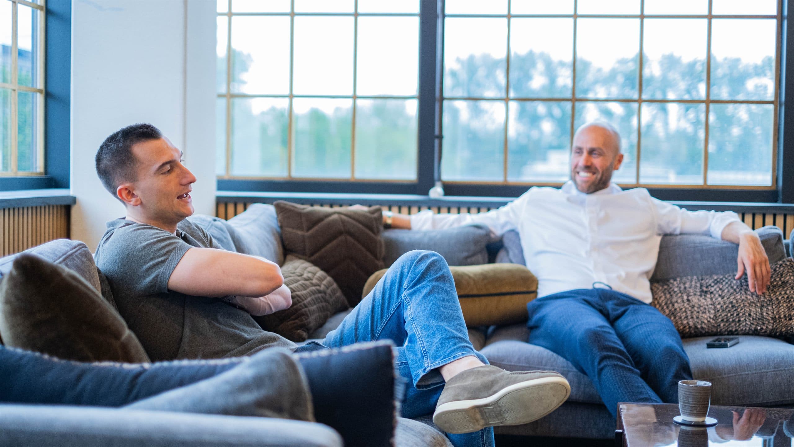 Twee professionals in gesprek aan een tafel in een Amsterdams kantoor aan de gracht